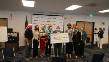 Group posing for photo with large check. 